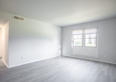 A spacious empty room featuring hardwood floors and pristine white walls, creating a bright and airy atmosphere